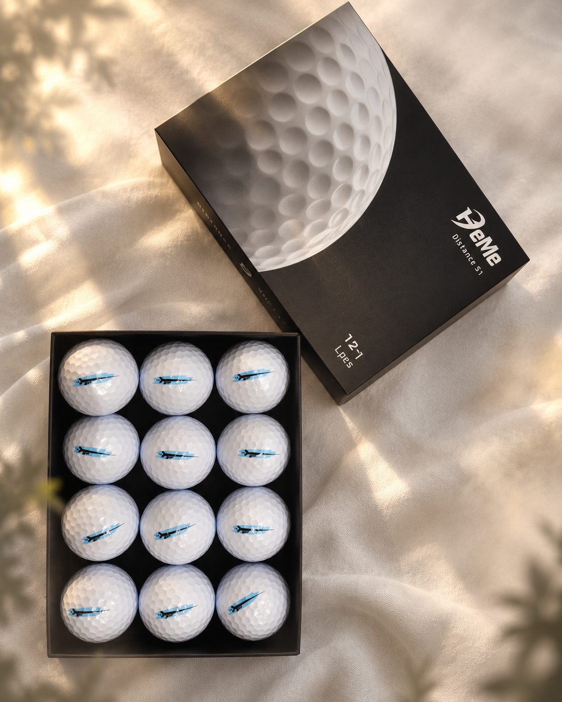 HeMe Distance S1 black presentation box and twelve white golf balls in warm golden light